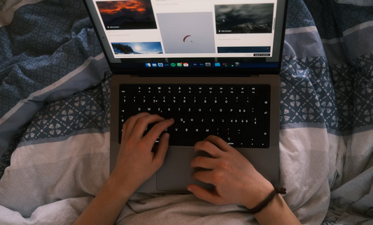 En person som skriver på en laptop i sängen